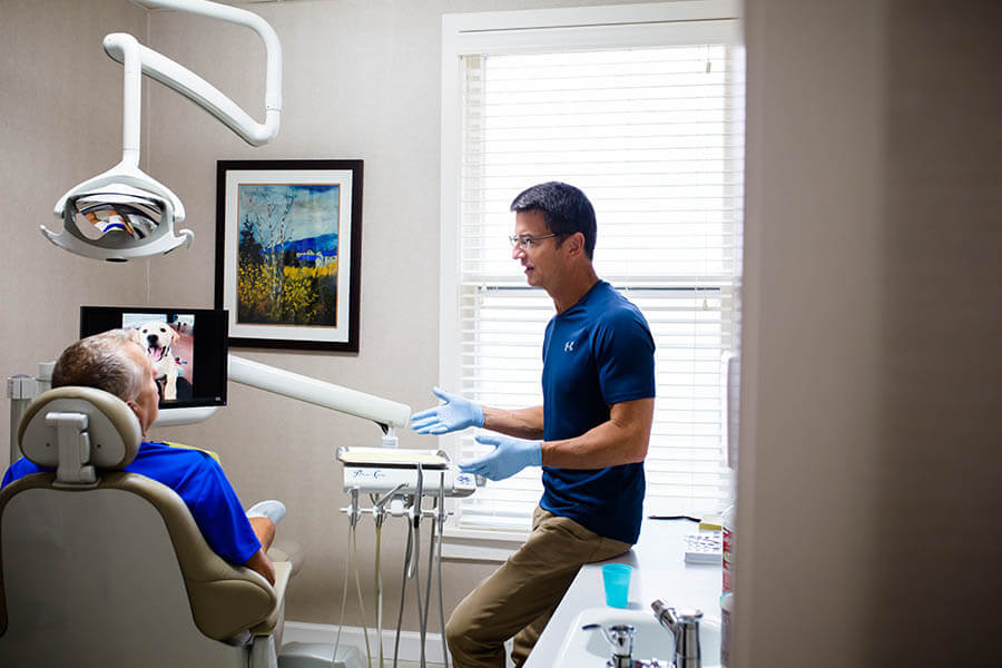 dentist explaining a procedure to a patient sitting in a dentist chair